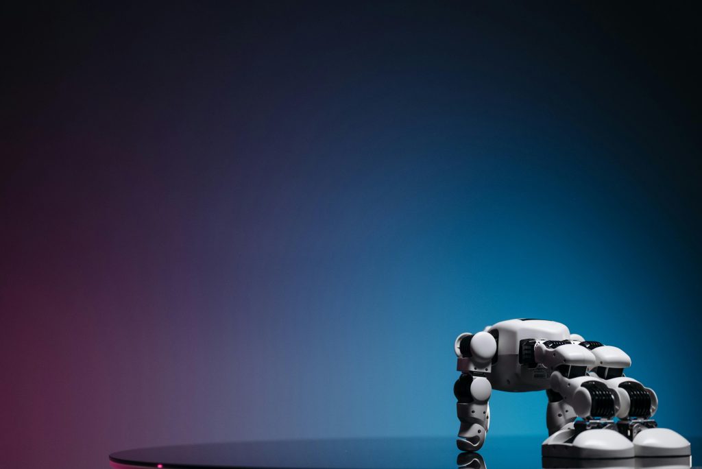 A close-up of a futuristic robot toy on a reflective surface against a gradient background.